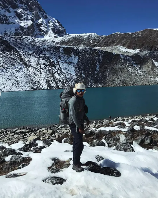 Surjan Syangdan at a high glacial lake surrounded by snow peaks