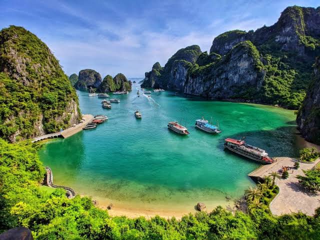 Limestone karsts and cruise boats in a sheltered lagoon at Ha Long Bay, Vietnam