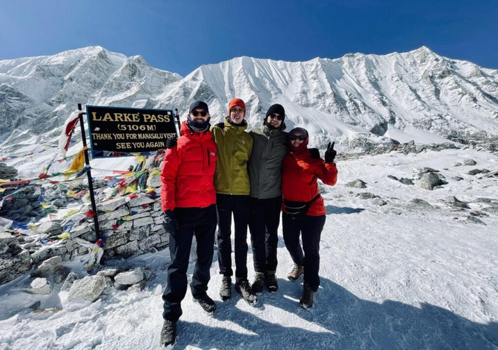 Trekking group celebrating at the Larkya La Pass sign, 5,106m
